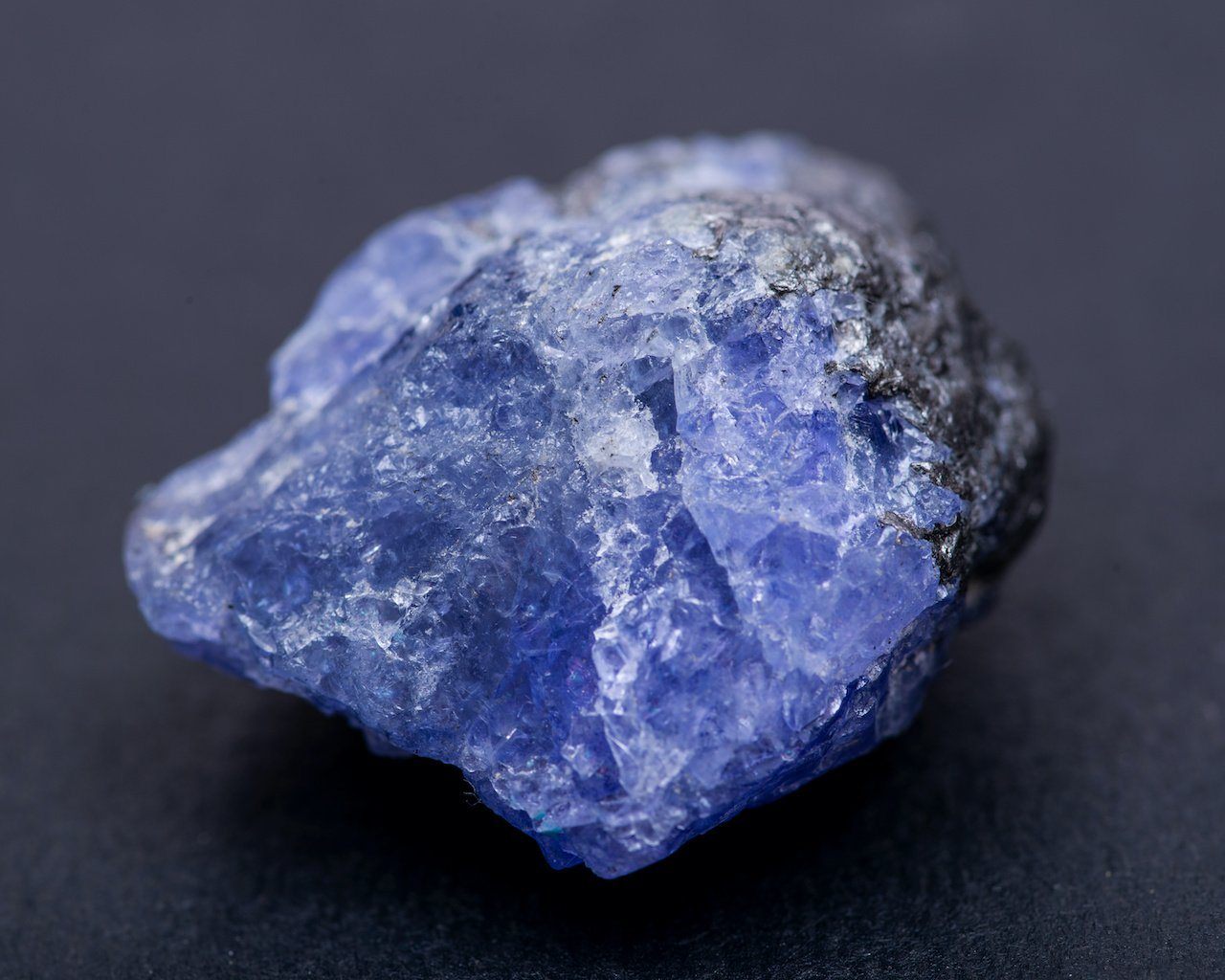 Rough violet blue tanzanite crystal on a dark background