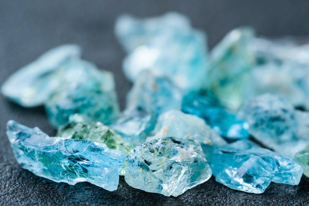 Rough pale blue aquamarine crystals on a dark surface