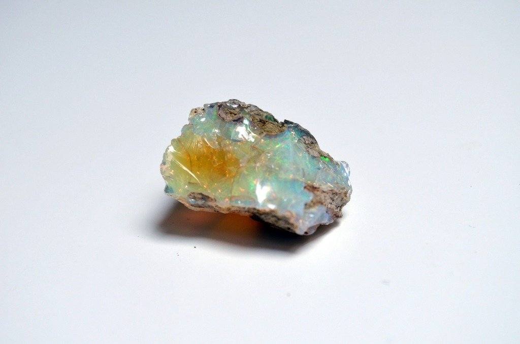 Rough opal with flashes of blue, green and orange on a white background