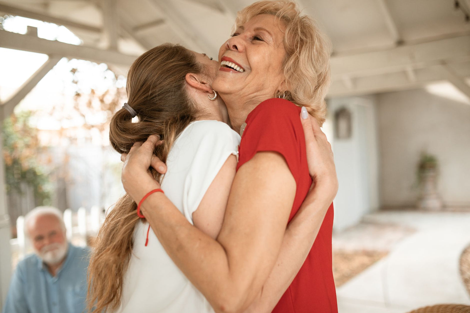 An adult daughter hugging her smiling older mother at home
