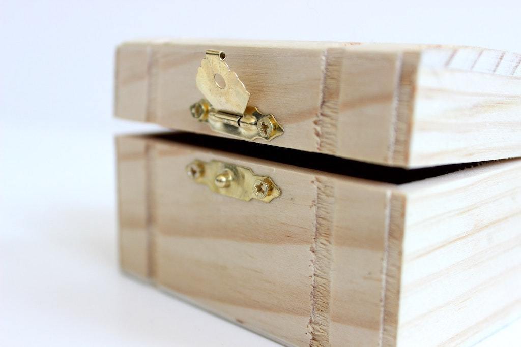 Small unfinished wooden jewelry box with a brass clasp, slightly open