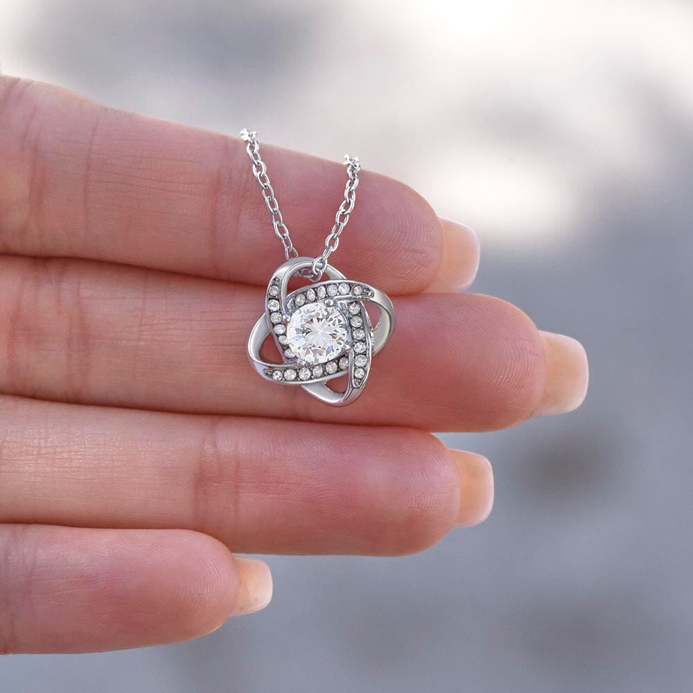 Hand holding the Love Knot Necklace pendant up close